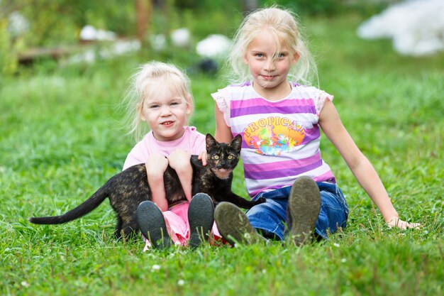 猫と緑の芝生で遊ぶ2人の女の子