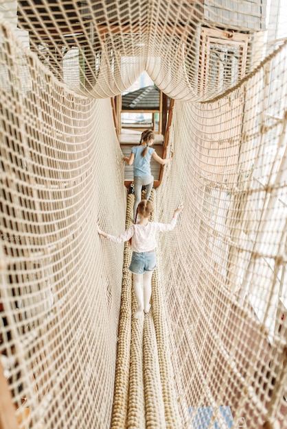 Two girls plays in rope net, children game center