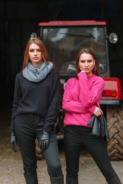 Two girls posing next to a tractor