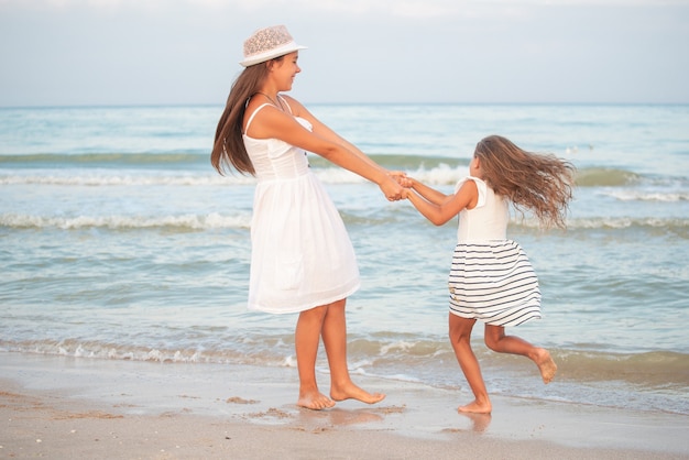 Two girls relax on the beach and walks the sea waves on a sunny summer evening during vacation