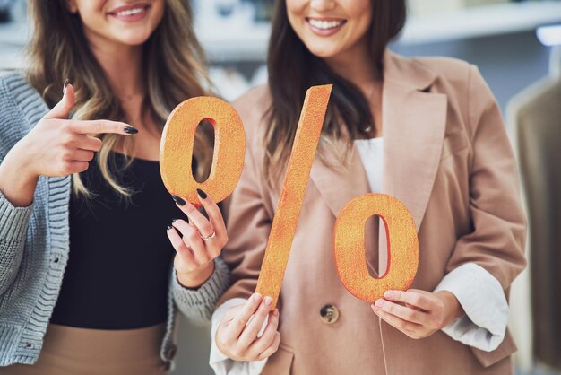 Photo two girls on shopping holding sale percentage sign. high quality photo