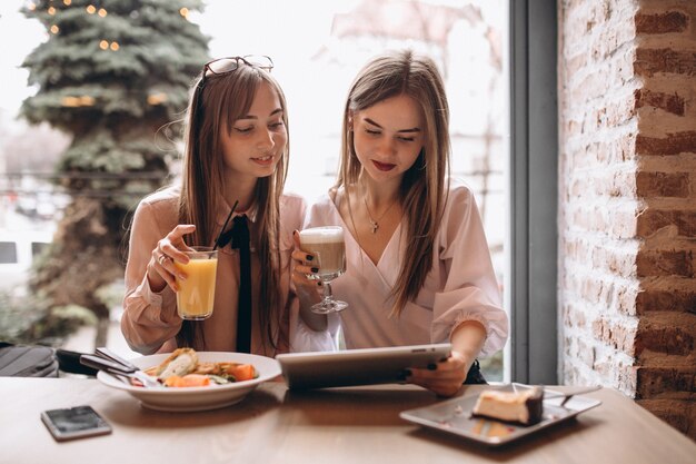 Two girls shopping on tablet in a cafe