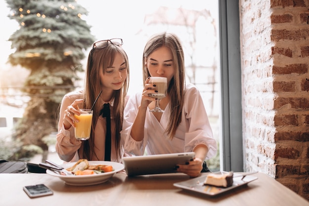 Two girls shopping on tablet in a cafe