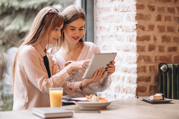 Two girls shopping on tablet in a cafe