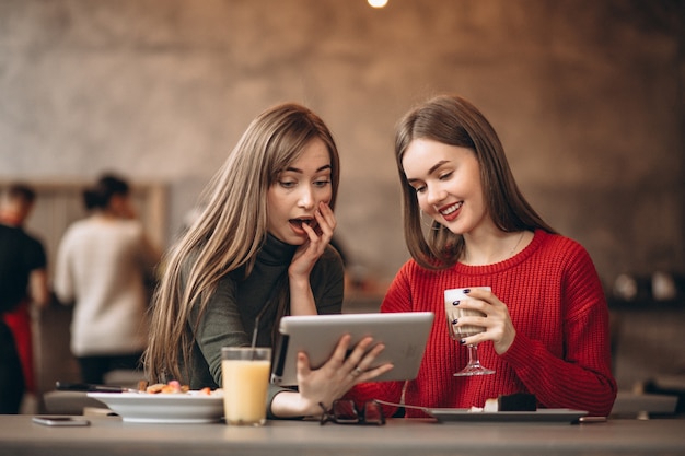 Two girls shopping on tablet in a cafe