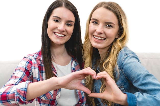 Photo the two girls show the heart symbol on the white background