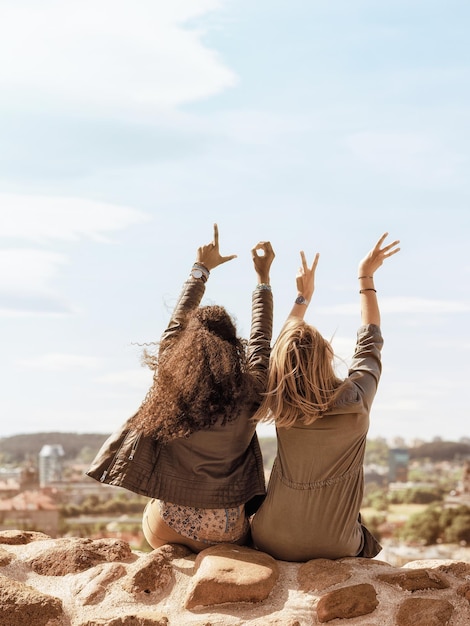 Two girls showing love sign with their fingers and enjoying the city skyline concept