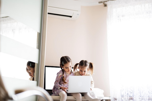 Two girls sisters watching on laptop Technology and home concept