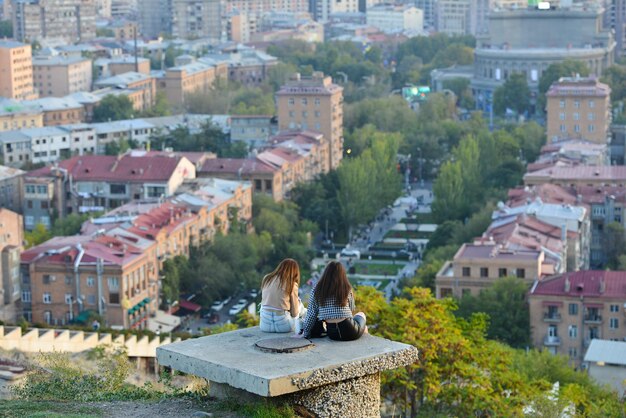 Фото Две девушки сидят и разговаривают, наслаждаясь видом на город ереван в армении