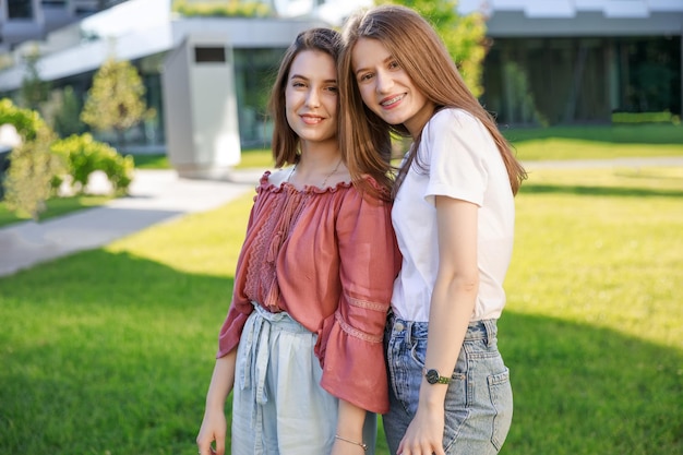 Two girls teenagers walking on green grass autumn walk early autumn best friends