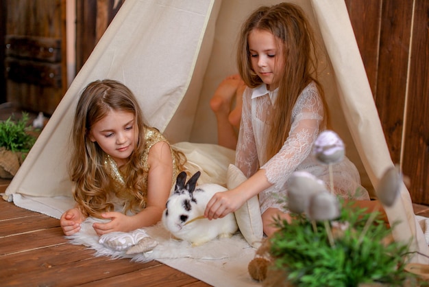 two girls in a tent wigwam with a rabbit, easter theme