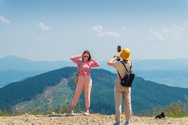 Two girls tourists are photographed on the phone against the background of a landscape of mountains