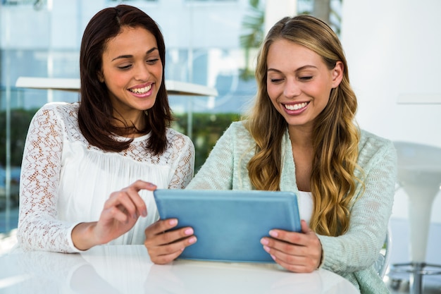 Two girls use a tablet and smiling