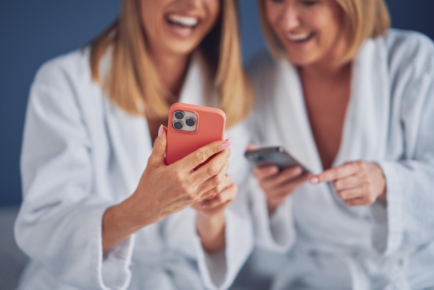 Two girls wearing bathrobe in spa or hotel having fun
