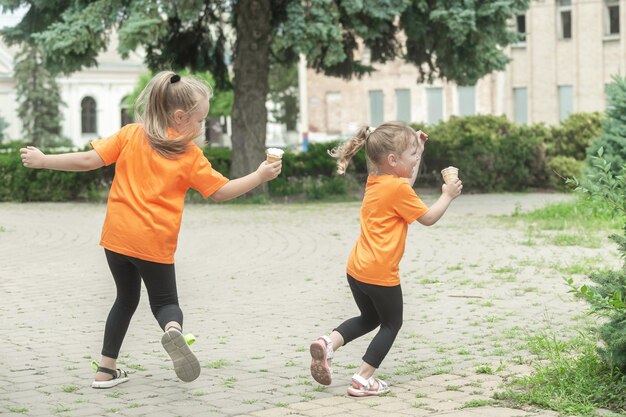 アイスクリームを持った 2 人の女の子が街の散歩でお互いの後を追う