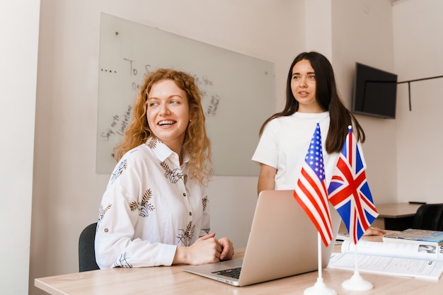 Photo two girls with laptop look at window in white class