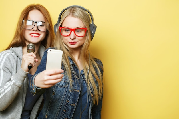 Two girls with a microphone singing and having fun together make selfie