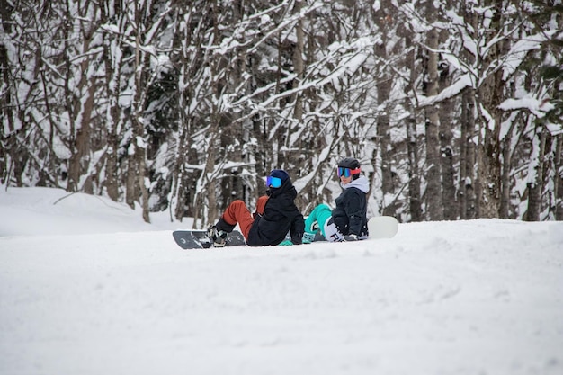 Due ragazze con uno snowboard si siedono sul lato della montagna