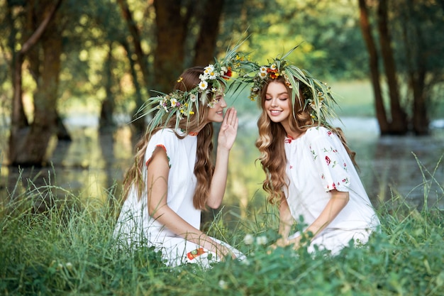 写真 手に花の花輪を持つ2人の女の子。真夏。アースデー。