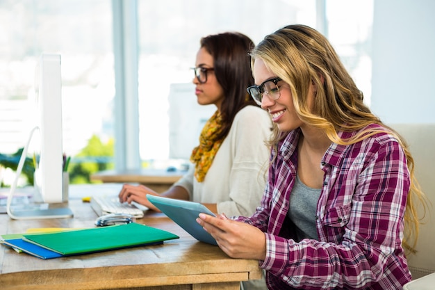 Two girls work at office on computer and tablet