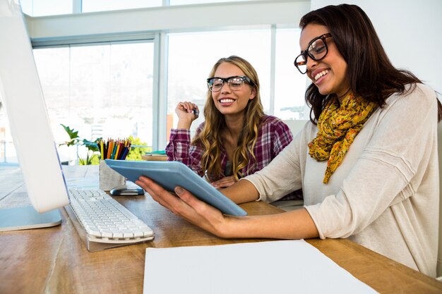 Due ragazze lavorano in ufficio su computer e tablet