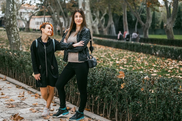 Two girls - young lesbian couple walking in autumn park and making fun. Smiling young lesbian couple hugging each other while standing together on city street