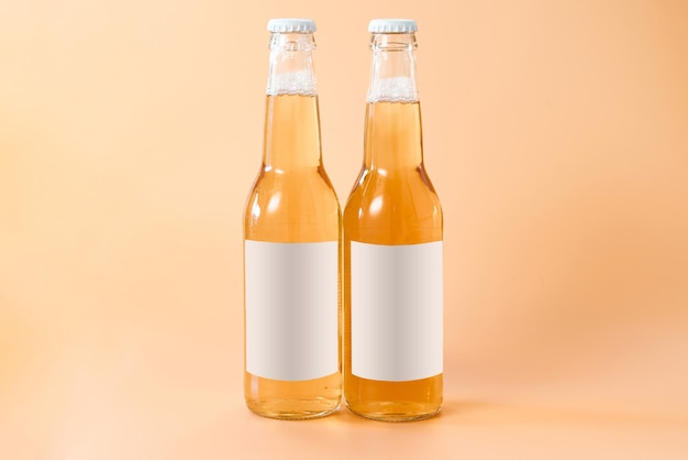 Две стеклянные бутылки пива с белой пустой этикеткой на оранжевом фоне Cool Golden Drunk Fluid Gold Brewed Алкогольный освежающий паб Chill Brand Product Bottle