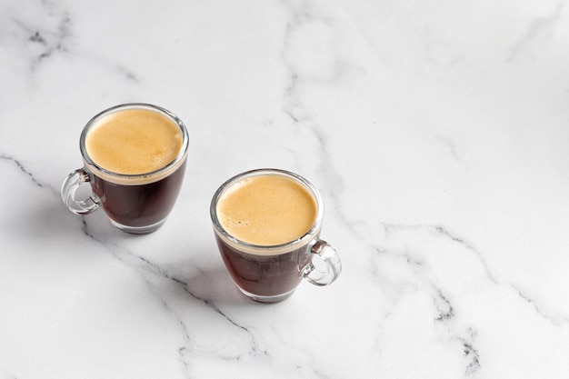 Две стеклянные чашки кофе с эспрессо утром на фоне белого мрамора Кружка аромата кофе