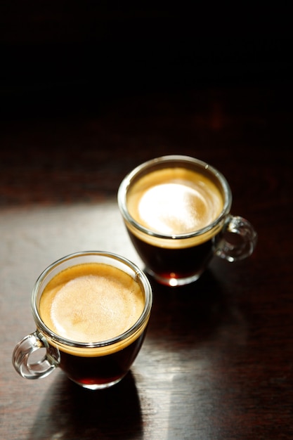 Two glass coffee cup with espresso near the window in morning on dark background