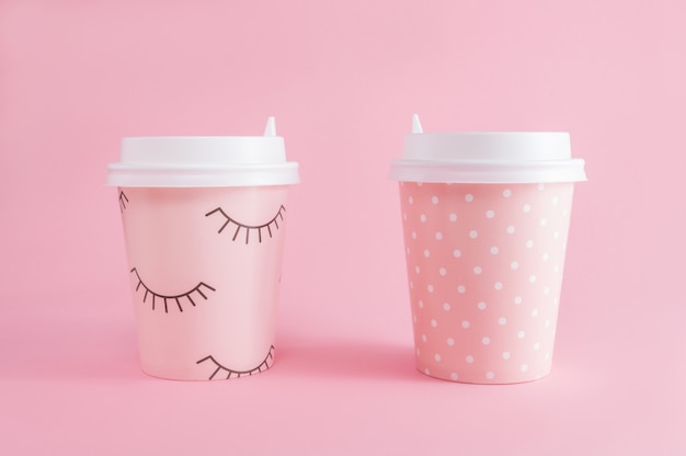 ピンクのパステル調の背景に2杯のコーヒーのテイクアウト