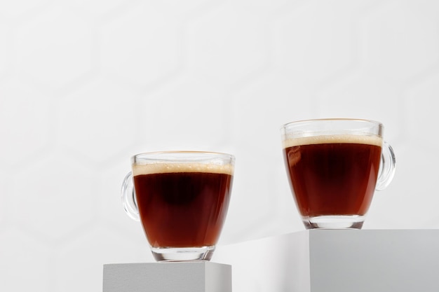 Two glass cups of coffee espresso on white podiums and tile background Aroma Drink on podium