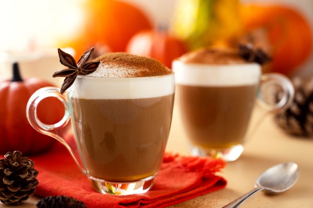 Two glass cups of pumpkin autumn latte warm drink with whipped cream. Autumn cozy beverage.