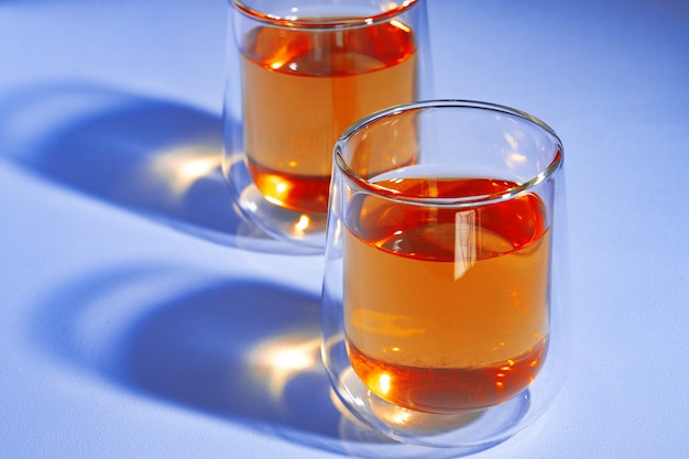 Two glass cups of tea on blue surface