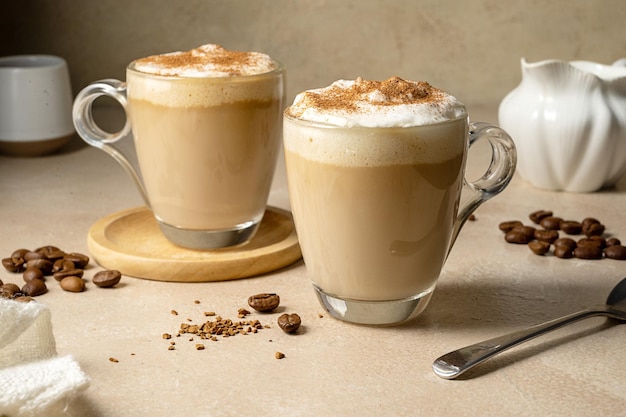 Two glass cups with coffee drink latte with milk foam and cinnamon