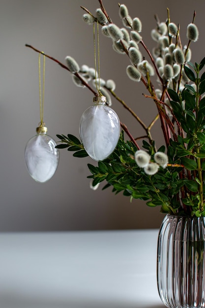 Two glass Easter eggs on willow branches in a glass vase