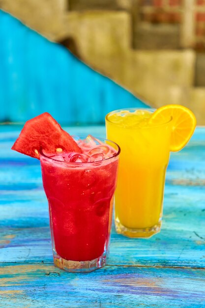 Two glass glasses with refreshing drinks from orange and watermelon juice.