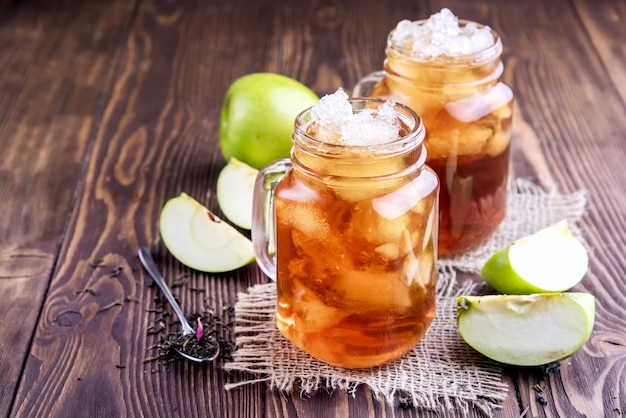 Two glass jars with iced tea on rustic background