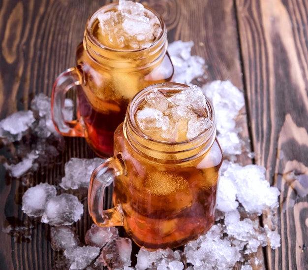 Two glass jars with iced tea on rustic background