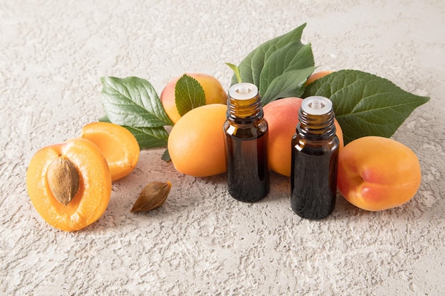 Two glass medical bottles with natural apricot kernel oil on the background of ripe fruit the concept of rejuvenation nutrition skin restoration