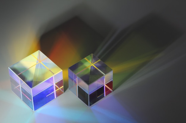 Foto primo piano di due cubetti di prisma di vetro rifrangono la luce e proiettano ombre colorate