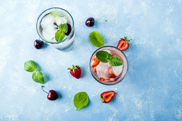 Two glass of refreshing cool detox drink with strawberry, cherry and mint