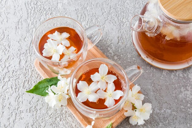 Two glass transparent cups with aromatic jasmine tea on a wooden tray tea teapot with freshly brewed tea tea time