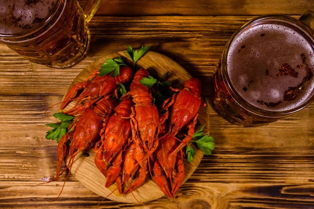 Two glasses of beer and boiled crayfish on rustic wooden table