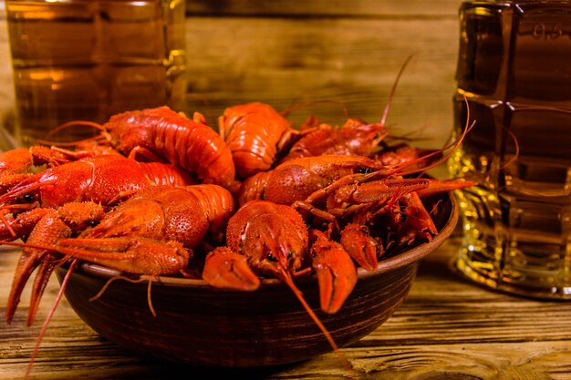 Two glasses of beer and boiled crayfish on wooden table