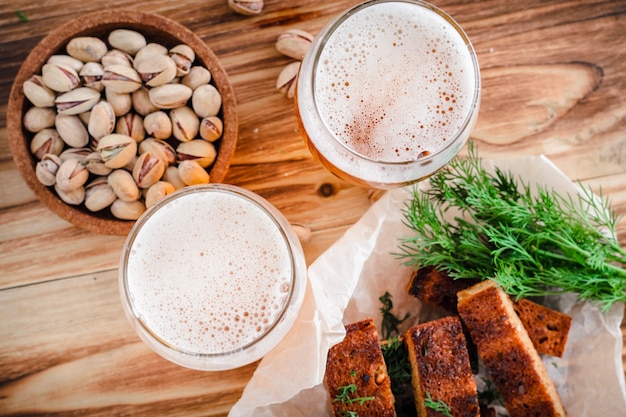 Two glasses of beer and pistachios on a wooden table