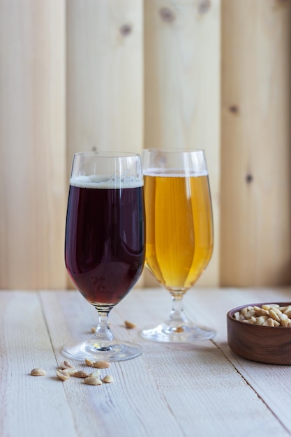 Two glasses of beer on wood background with pistachios