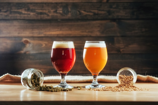 Two glasses of beer on a wooden table grains