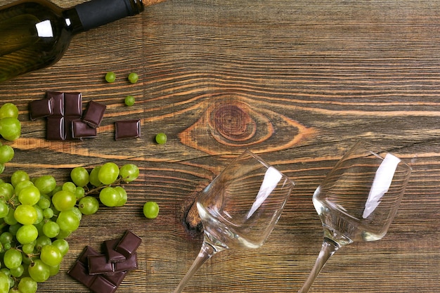 Two glasses bottle of white wine and grape on a wooden table