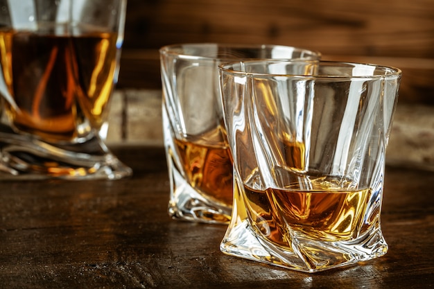 Two glasses of brandy or cognac and bottle on the wooden table