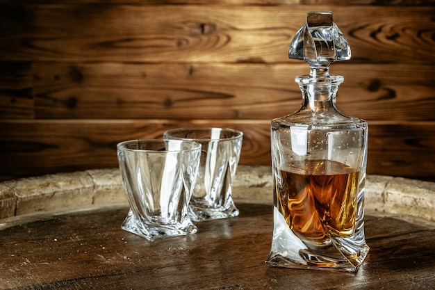 Two glasses of brandy or cognac and bottle on the wooden table